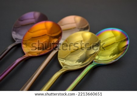 Multicolored table spoons on a plain black background, picture for an article about tableware or cutlery, with a copyspace