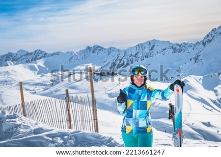 Close up portrait of a woman skier showing OK sign on the top of the snowy Pyrenees Mountains. Winter ski holidays in El Tarter, Grandvalira, Andorra