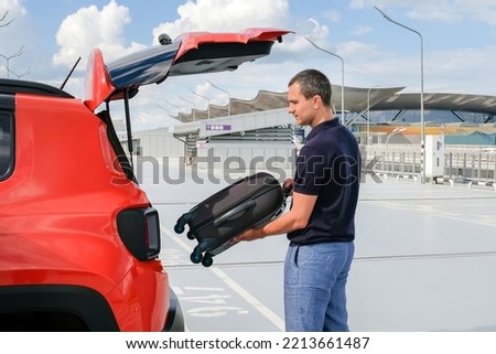 A man puts his suitcase in the trunk of a car. Business trip, business trip, vacation concept
