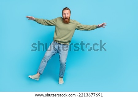Full size photo of nice young guy balancing one leg falling scared height tightrope wear khaki look isolated on cyan color background