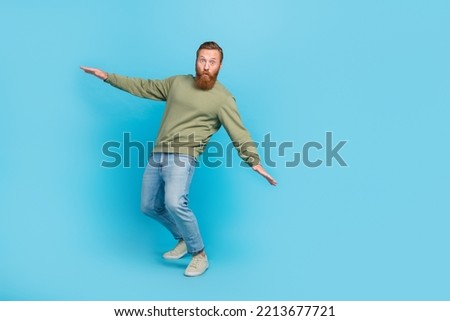 Full size photo of nice young guy try keep balance falling leaning surfing nervous wear khaki clothes isolated on cyan color background