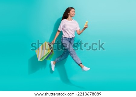 Full size photo of positive cheerful woman flying jumping hold smartphone shopping bags look empty space isolated on teal color background