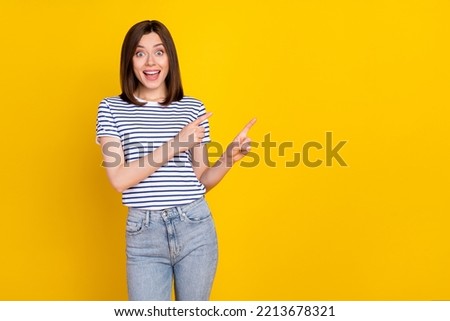 Photo of gorgeous lovely positive girl with wear striped t-shirt indicating empty space news promo isolated on yellow color background