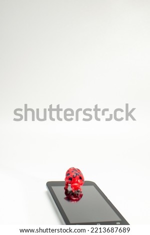 A cellphone and a toy bug on a white isolate background
