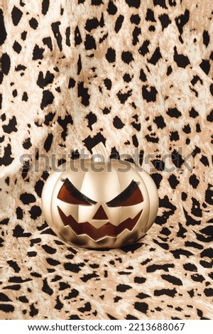 Gold Halloween pumpkin with lashes on a leopard print background. Fashion aesthetic minimal fall concept. Monochromatic colors.