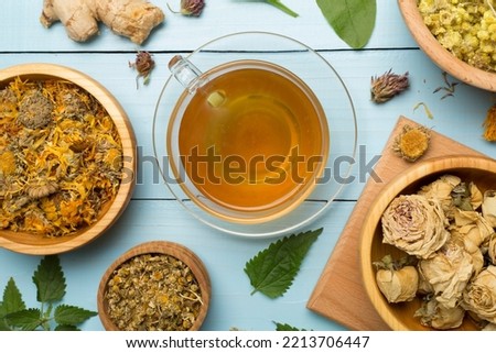 Herbal tea with ingredients on wooden background, top view.