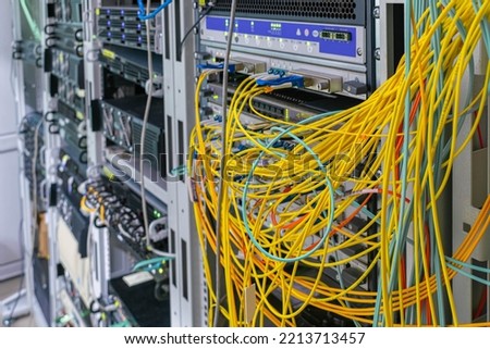 There is a rack with network equipment in the server room. There are a lot of messy wires on the server patch panel Royalty-Free Stock Photo #2213713457