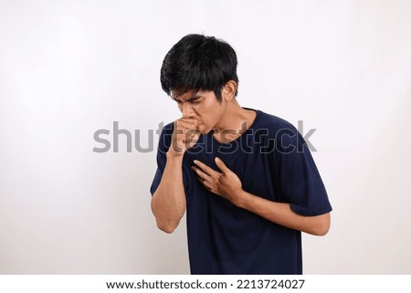 Young asian man in casual coughing into his fist while holding his chest. Isolated on white background with copyspace Royalty-Free Stock Photo #2213724027
