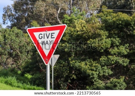 give way sign against backdrop of trees