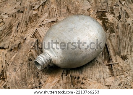 An old aluminum flask on a wood background. An old army flask of rounded shape.