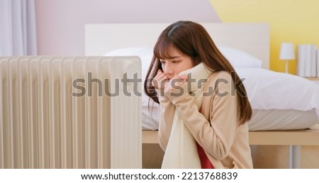 asian woman feel cold and is using heating to warm up in winter sitting on floor at home Royalty-Free Stock Photo #2213768839