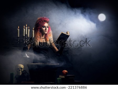 Beautiful witch making the witchcraft over the smoky background. Halloween image.