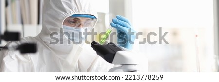 Scientist in protective suit studies toxic poisonous liquids in laboratory. Hazardous production of chemicals concept