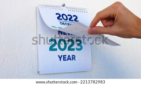 Close-up of male hands flipping through the December page of 2022 wall calendar followed by the title page of a new 2023 calendar Royalty-Free Stock Photo #2213782983