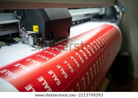 Printing stickers for sale on the printing table. Flyers with the words sale.Preparing for Black Friday in stores. Printing of stickers for the customer on a printing plotter  Royalty-Free Stock Photo #2213798393