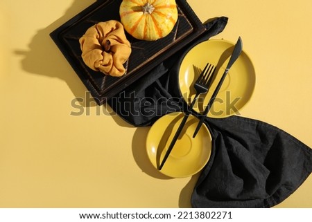 Autumn table setting with pumpkin on yellow background