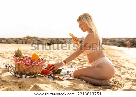 Cheerful young woman enjoy at tropical sand beach. Young woman taking a picture of fruit on the beach