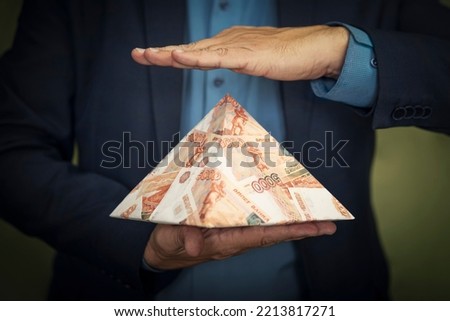 a pyramid scheme in the hands of a fraudster. The concept of exchange in financial markets is the collapse of the financial system of capitalism. Royalty-Free Stock Photo #2213817271