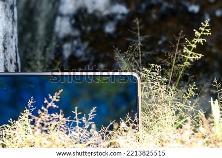 Photo of a smart phone in a green natural surface. SmartPhone in green grass.