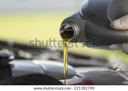 Close up of fresh oil being poured into a car during it's required service.  Royalty-Free Stock Photo #221382790