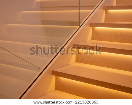 part of stairs in light marble with bright leds below the steps, wall with a glass plate Royalty-Free Stock Photo #2213828365