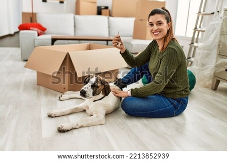 Young woman holding key sitting on floor with dog at home