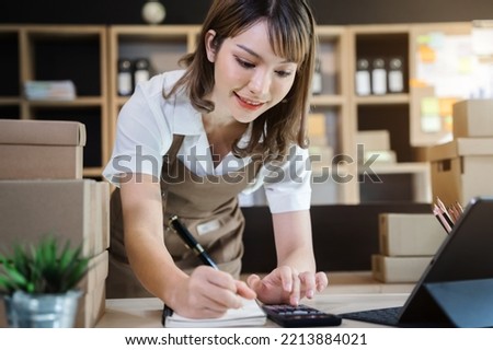 Entrepreneur using calculator with pencil in her hand, calculating financial expense at home office.