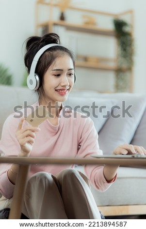 Happy young asian woman holding credit card and doing e-shopping at home, online shopping, e-commerce, internet banking and spending money, working from home concept.