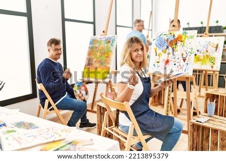 Group of middle age artist at art studio doing money gesture with hands, asking for salary payment, millionaire business 