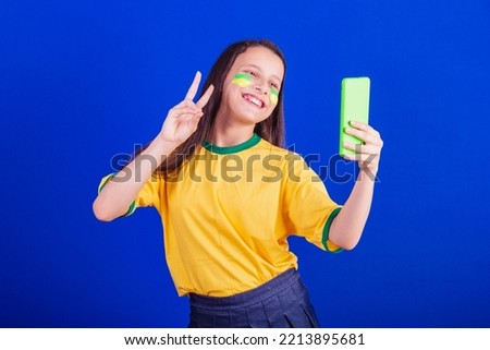 young girl, soccer fan from Brazil. holding cellphone, selfie, self portrait. Smartphone. applications.