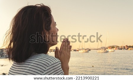 Young woman praying on beach. Blank copy space on sky and blue sea for advertising texts.