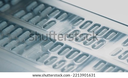 Blister packs with medicinal capsules move along the conveyor. Stage of fabrication. Plastic package with capsule meds. Medication capsules in blisters. Pharmaceutical factory production line Royalty-Free Stock Photo #2213901631