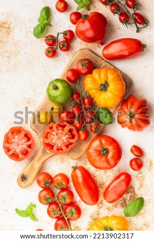 Selection of organic large heirloom and cherry tomatoes on white cream brown concrete background, selective focus Royalty-Free Stock Photo #2213902317