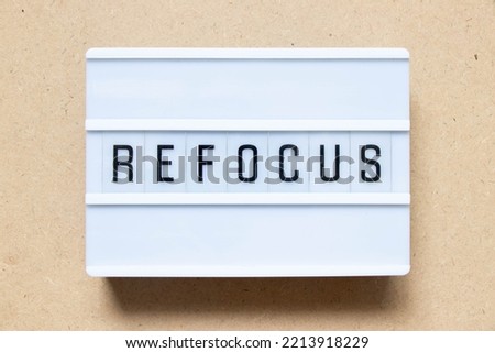 Lightbox with word refocus on wood background