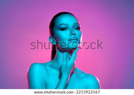 High fashion model metal silver lips and face woman in colorful bright neon UV blue and purple lights, posing in studio, beautiful girl, glowing makeup, colorful makeup. Glitter Bright Neon Makeup Royalty-Free Stock Photo #2213922567