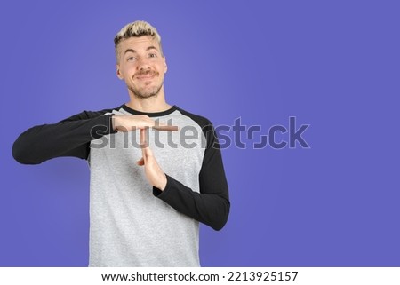 Man standing while asking for time put with his hands on isolated purple background. Isolated purple background studio shot