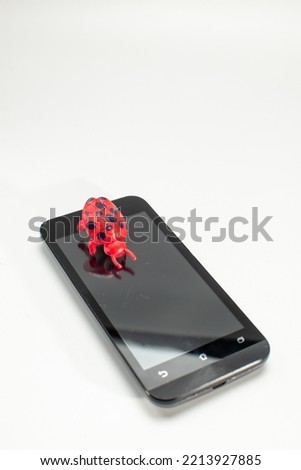 A cellphone and a toy bug on a white isolate background