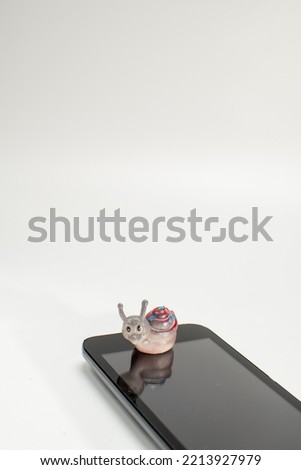 A cellphone and a toy snail on a white isolate background