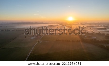 Aerial Drone Shot of a beautiful Green and Yellow Agricultural Plantations Bordering with Wild Forests in Belgium, Europe with the golden rays of sun creating a magical blanket over the green