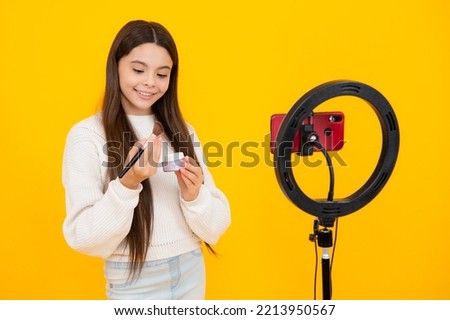 Beauty blog, presenting makeup cosmetics powder and brush. Teen girl speaking in front of camera for vlog isolated on yellow background. Teenager working as blogger, recording video blog.
