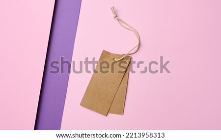 Empty brown tags on a rope, pink background. Price template, top view
