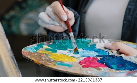 Closeup woman female hand artist painter paints draws creating new art work on canvas in workshop lesson of painting enjoying process of drawing creating picture using brush applying oil paint palette