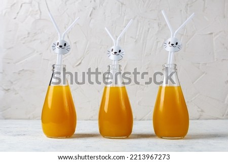 Orange drink decorated with white rabbit on light background for children party. Funny food concept for kids