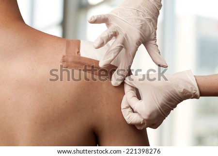 Medical assistant changes the dressing of a wound at the emergency room Royalty-Free Stock Photo #221398276