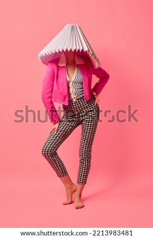 Weird people concept. Creative portrait of young girl in avant-garde style image isolated over pink background. Vivid style, queer, art, fashion Stylish model in white lampshade. Royalty-Free Stock Photo #2213983481