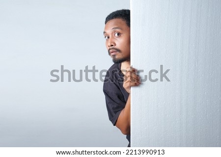 funny curious man peeking behind the wall Royalty-Free Stock Photo #2213990913