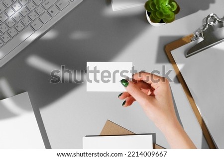 Woman's hand giving businesscard above the working table Royalty-Free Stock Photo #2214009667
