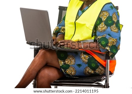 female engineer in protective helmet sitting in chair on white background working using laptop.