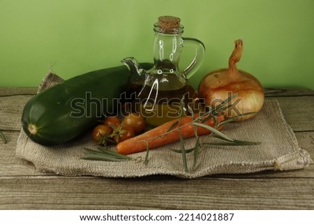 A close-up of a still life of extra virgin olive oil, with its slices of homemade bread, olives and olive branch. All on a green and brown wooden background.