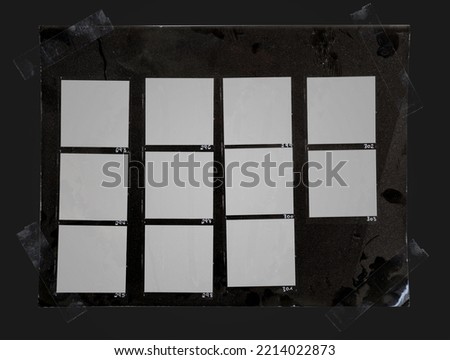 macro photo of black and white handcopy contact sheet with empty film frames fixed by transparent sticker tape on dark background.